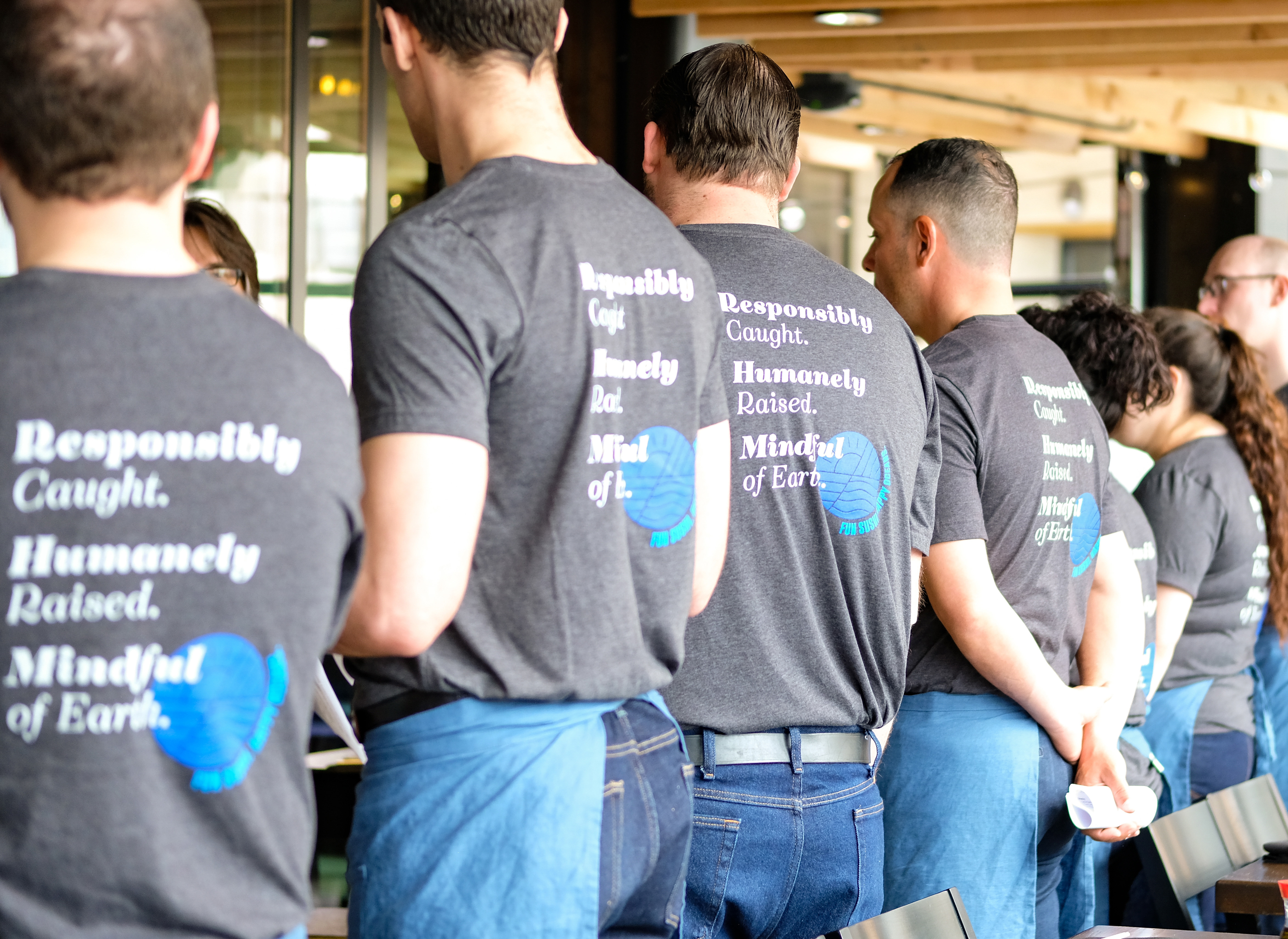 A line of Blue Sushi Sake Grill employees standing together in matching t-shirts.