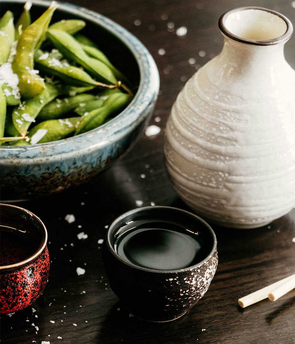 A bowl of edamame accompanied by soy sauce.